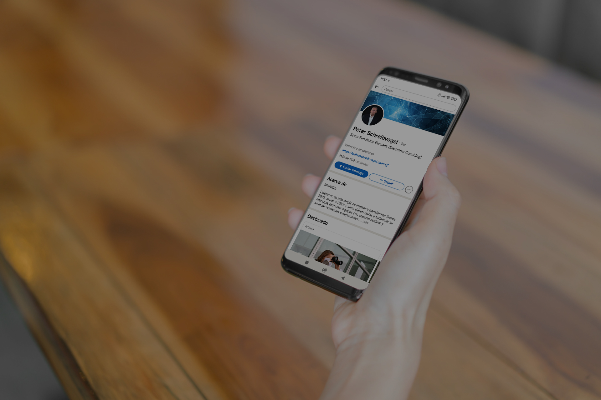 Mock up de un móvil en la mano de una persona. En la pantalla del móvil se puede ver el perfil de Linkedin de Peter Sheibvogel.