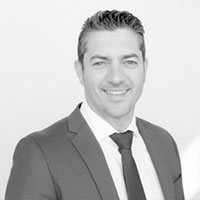 Retrato en blanco y negro de un hombre sonriente con traje, representando el equipo de Elmenut.